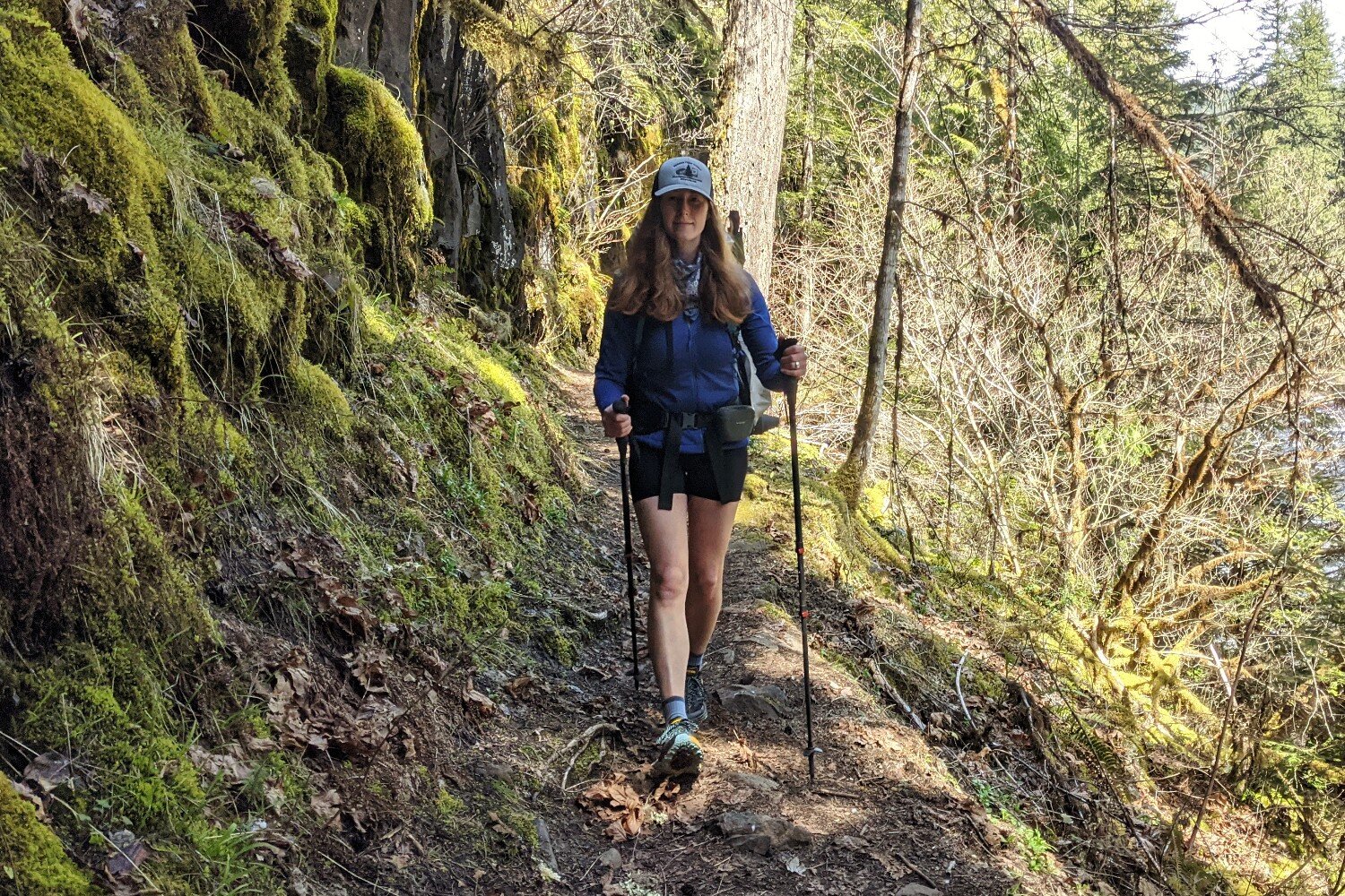 woman hiking next to a mossy rockwalls