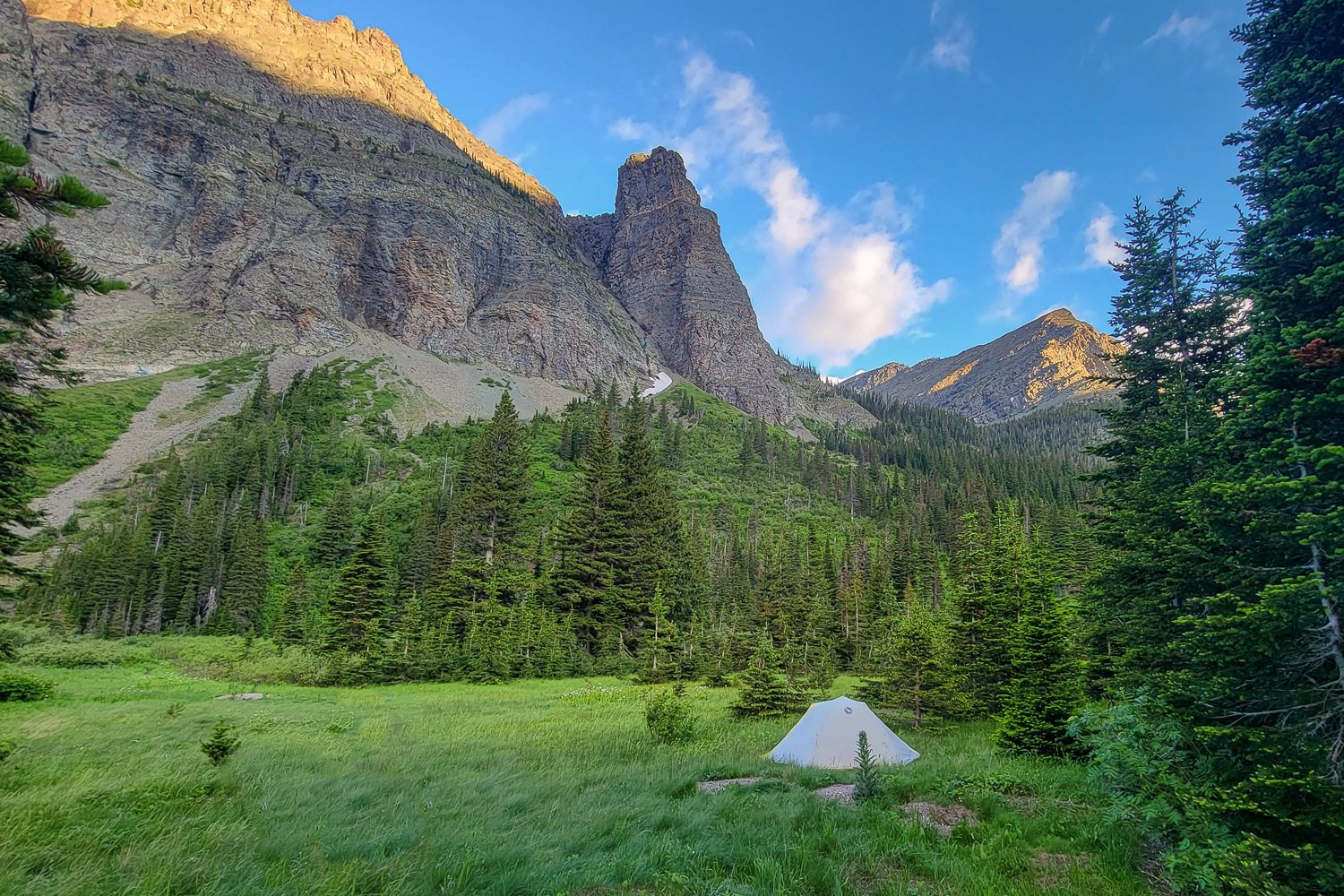 A tent setup in an expansive mountain valley.