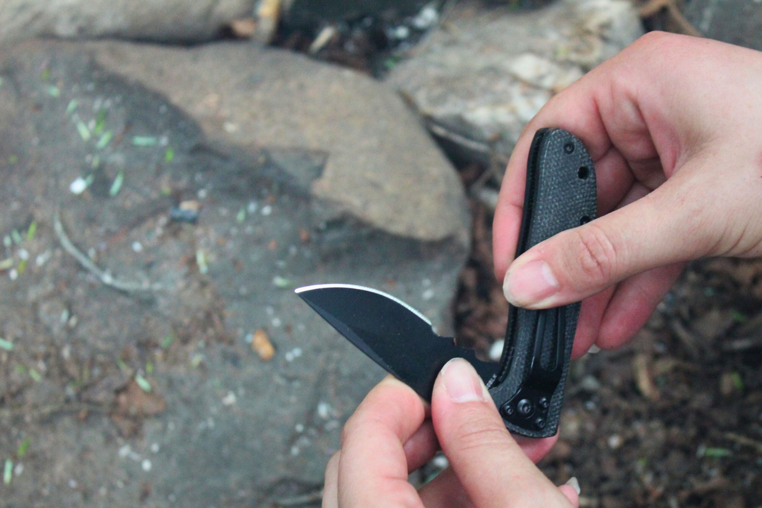 Holding the CRKT Drifter Pocket Knife partially open with rocks in the background