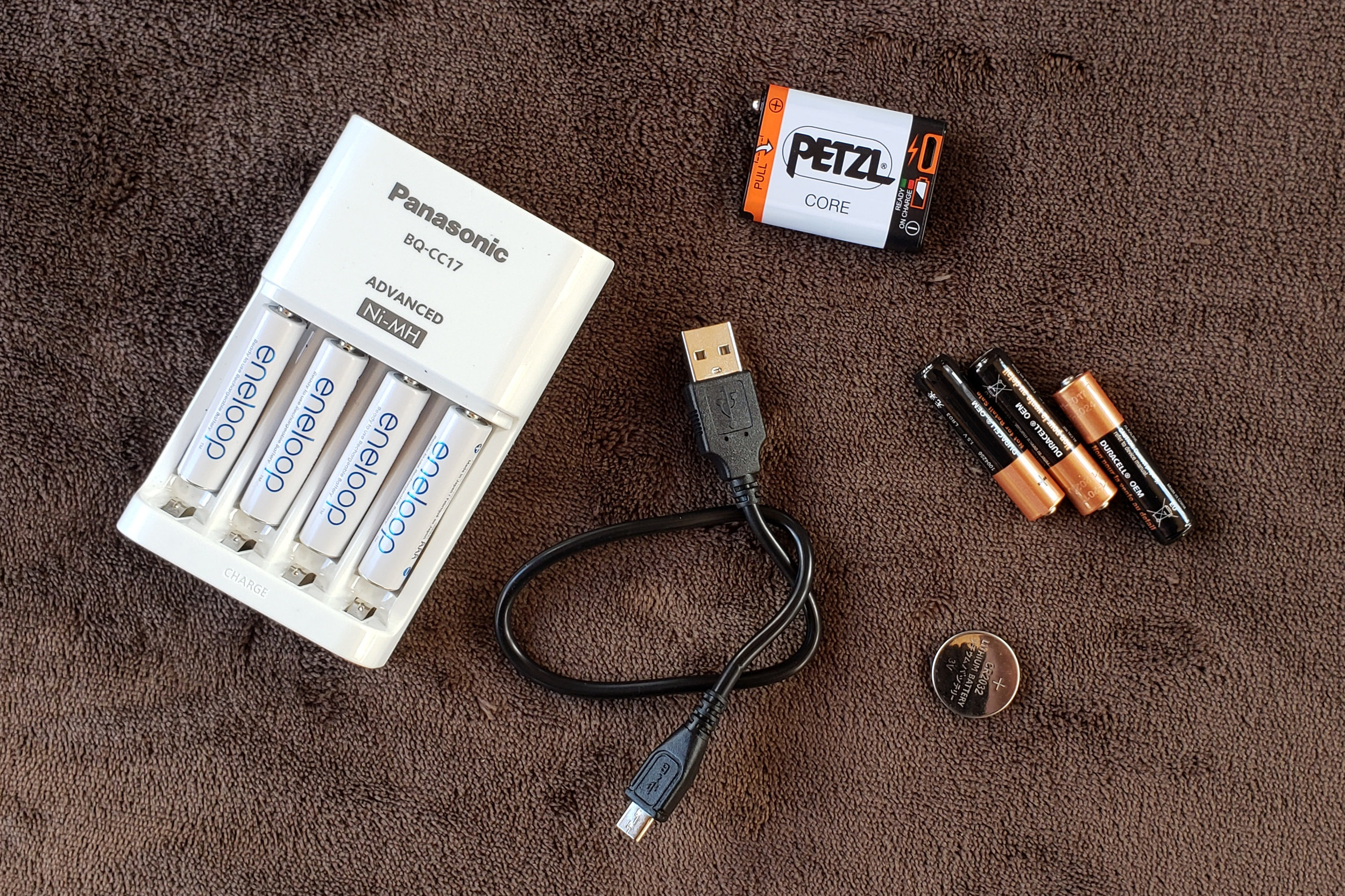 a display of different headlamp charging systems like a power usb cord, a rechargeable battery, lithium batteries, and button cell