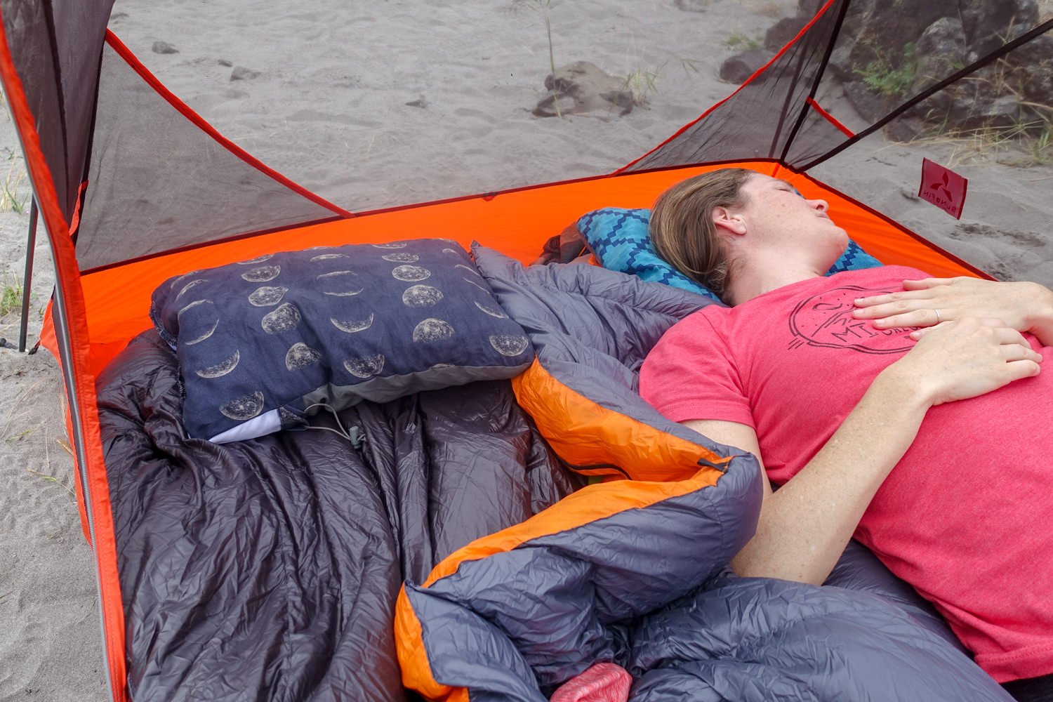 a camper resting in their tent with their head on a camp pillow