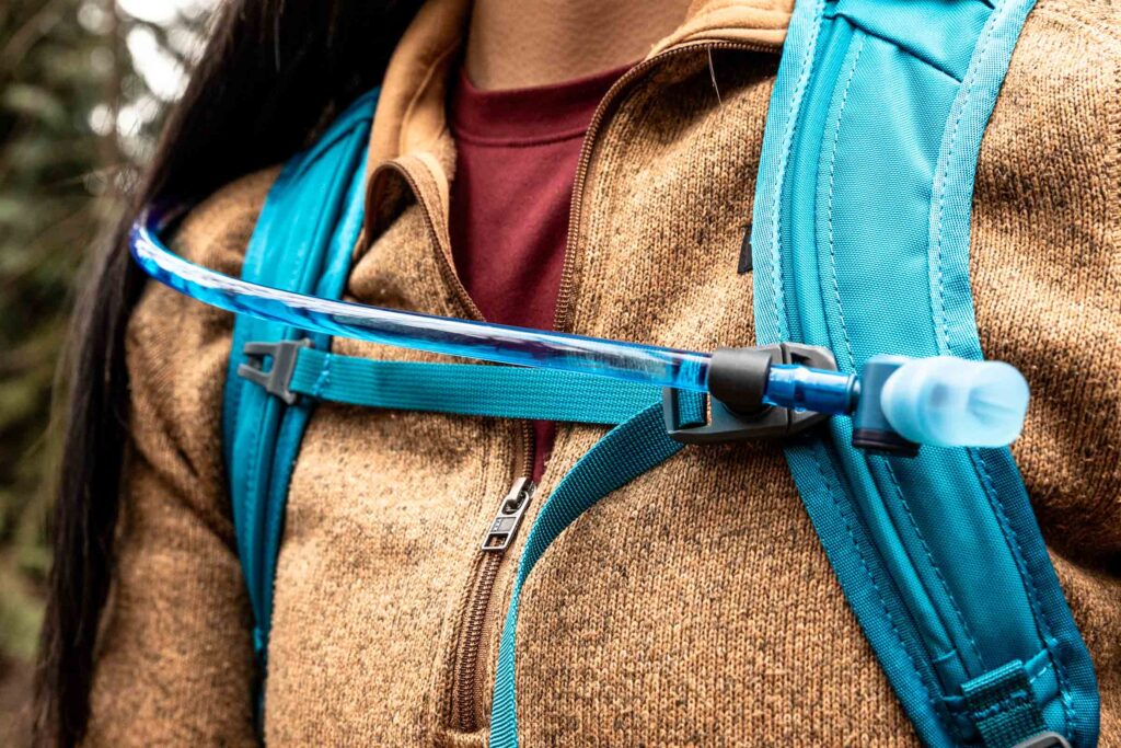 Details of Gregory Swift 16 H2O - a close up view of a person wearing the pack showing  the front straps and hydration hose