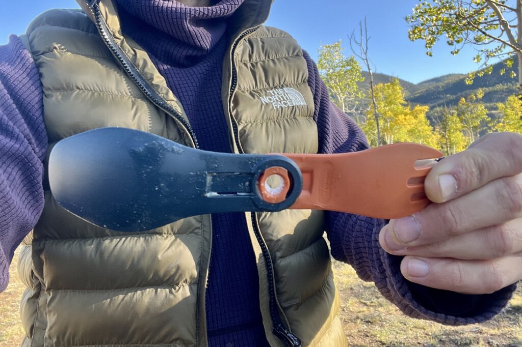 A hiker shows the camera a collapsible spork with food stuck in the spinning mechanism