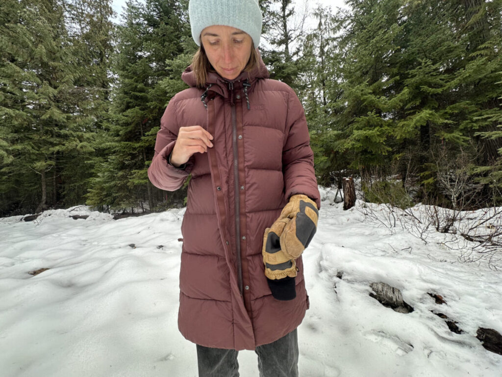 women buttoning a winter parka in a snowy forest