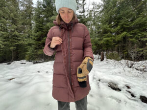 women buttoning a winter parka in a snowy forest