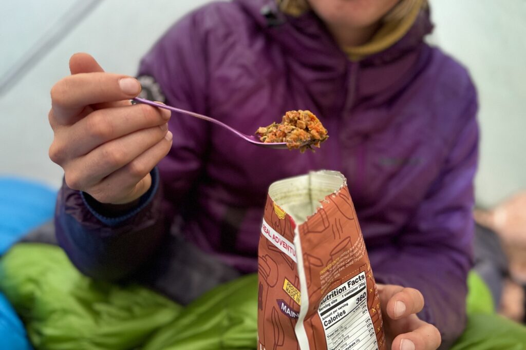 a hiker shows a bite of food on a purple titanium spork