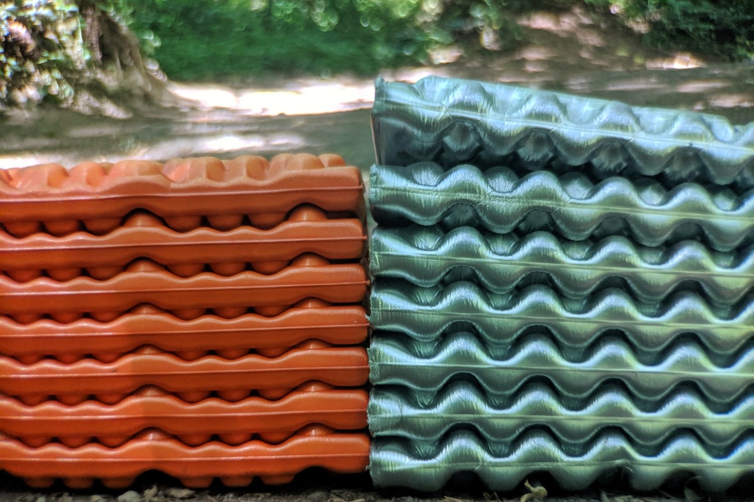 two closed cell foam sleeping pads folded up on the ground