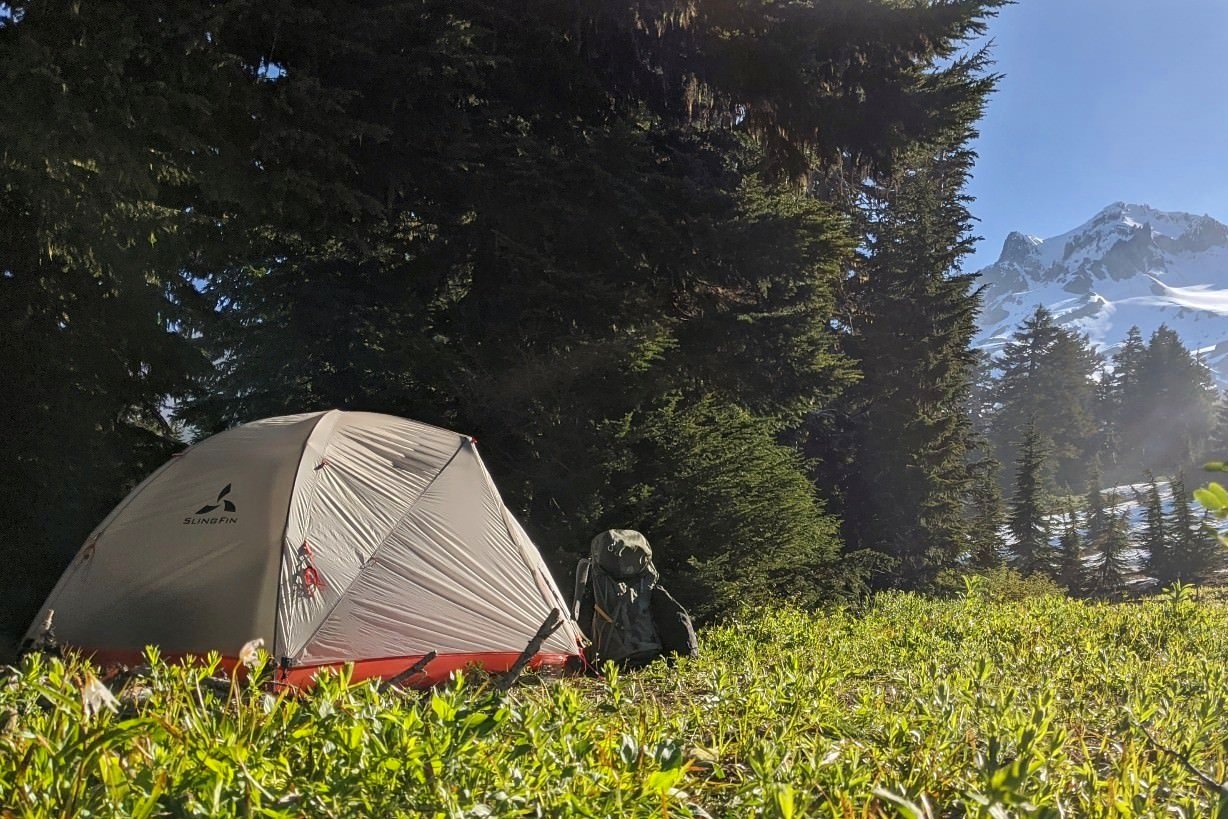 backpack propped up next to the sligfin portal backpacking tent with a snow capped volcano in the background