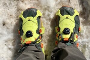 a POV view of a hikers feet with trail runners and ice cleats