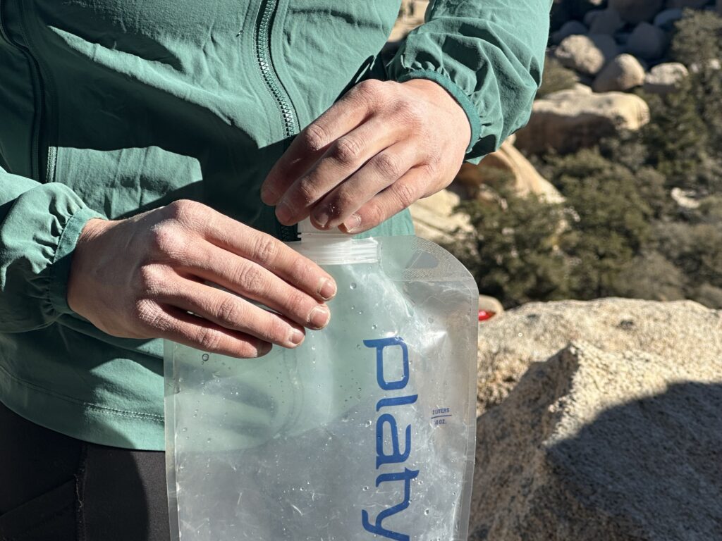 Close-up of a hiker holding the Platy and twisting the small cap back on.