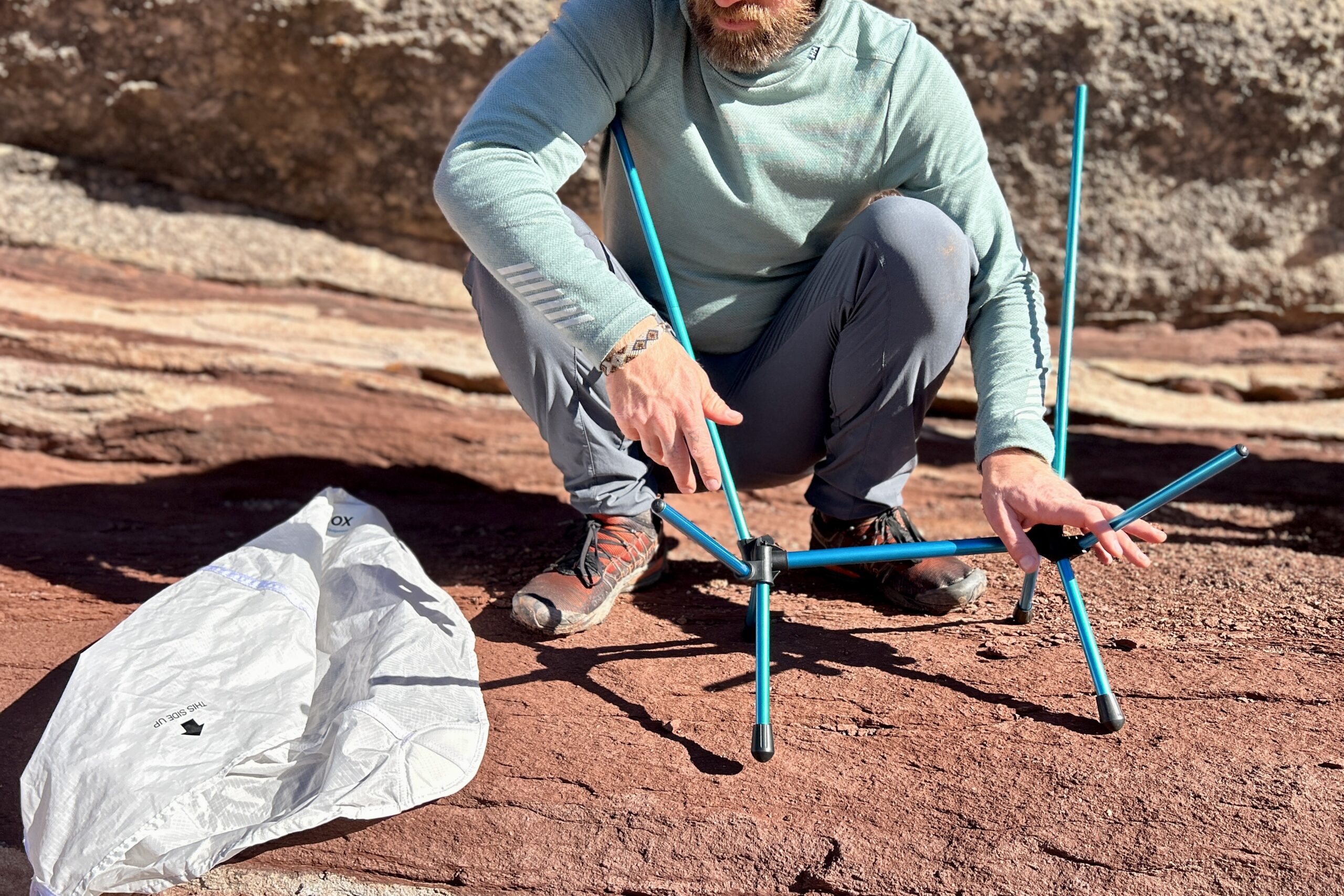Close up of a person setting up a small backpacking chair frame.