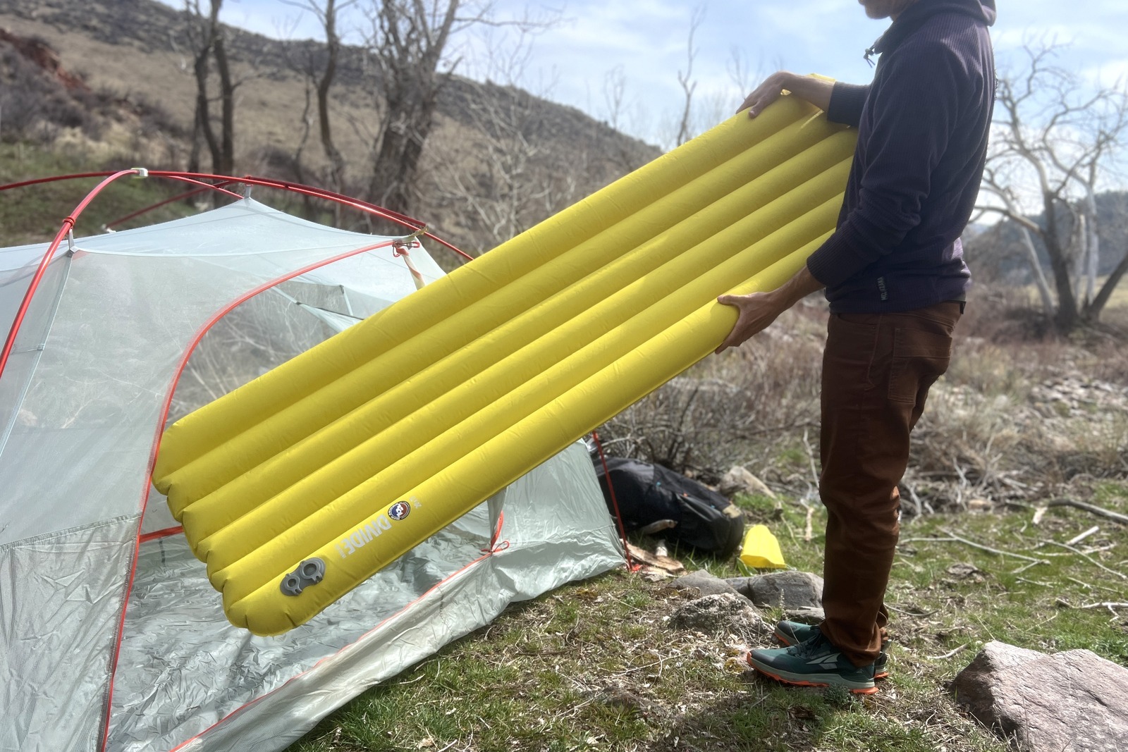 a hiker slides a yellow inflatable sleeping pad into a tent