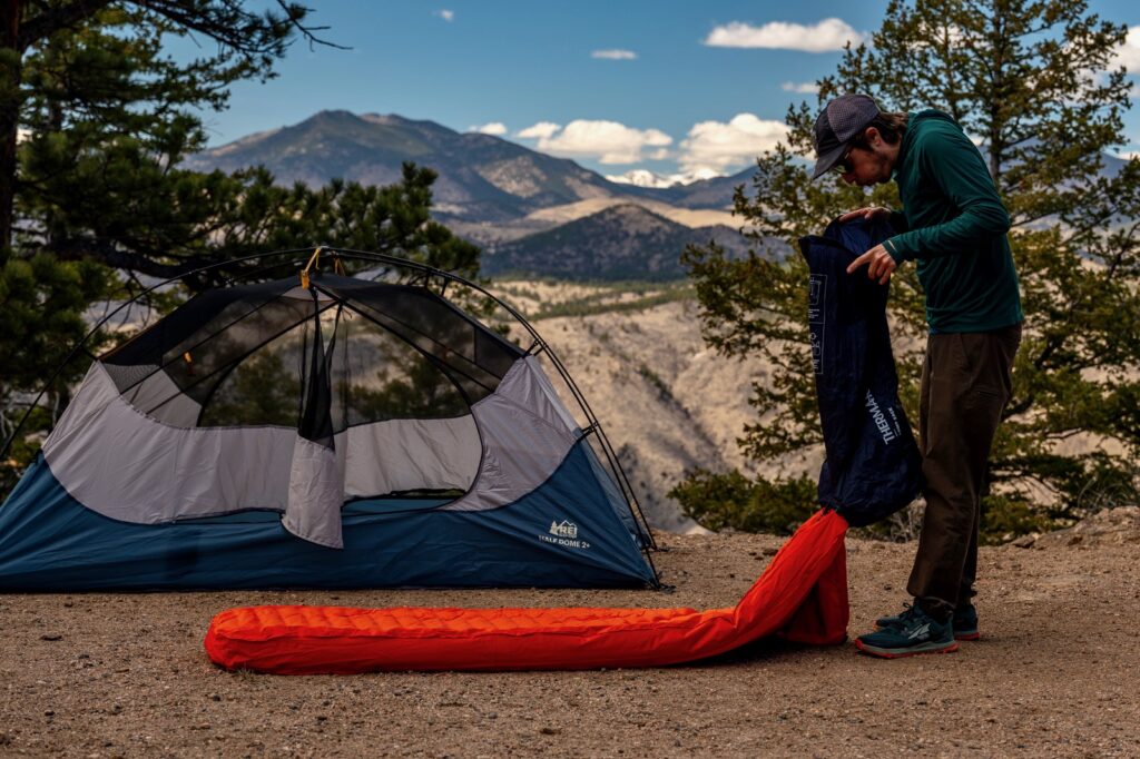 a hiker blowing air into a sleeping pad pump sack