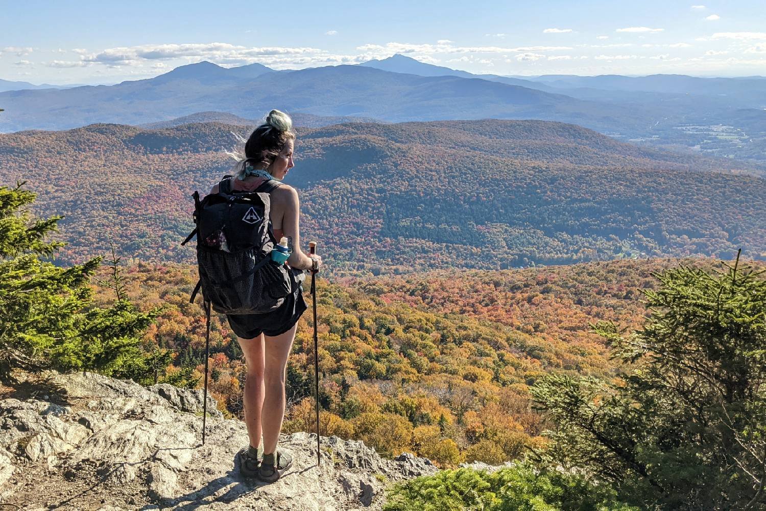 thru-hiker on a fall vista in vermont carrying trekking poles