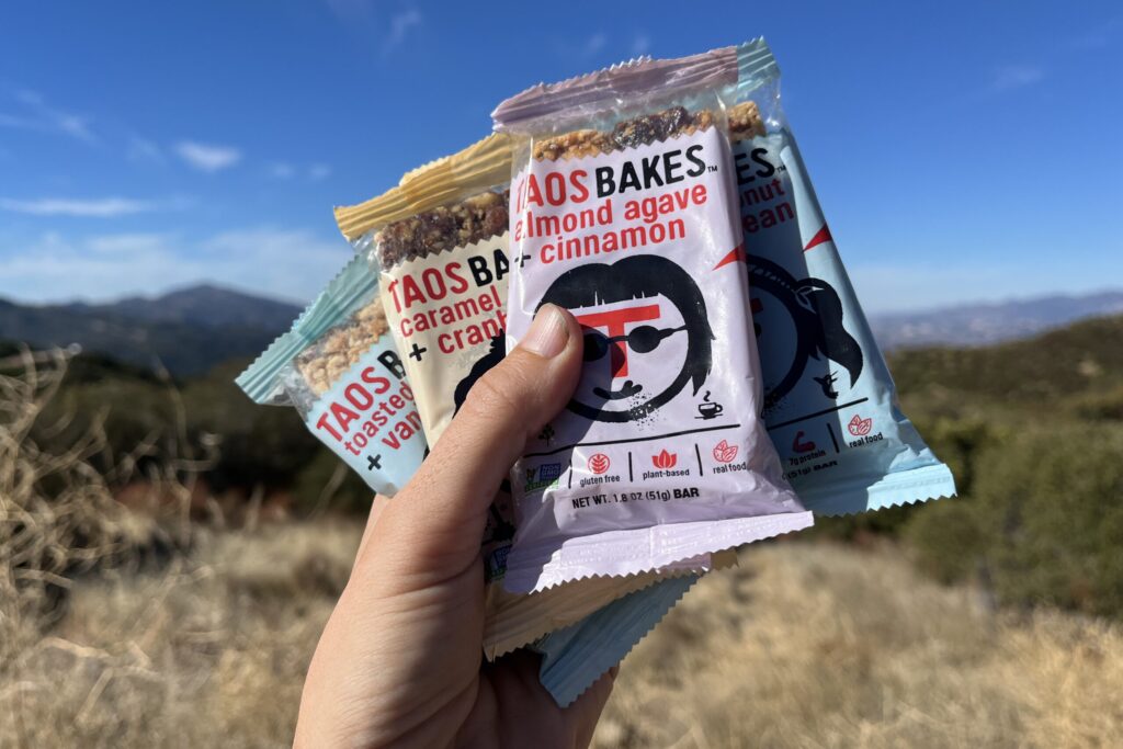 Hand holding Taos Bakes bar in mountainous setting