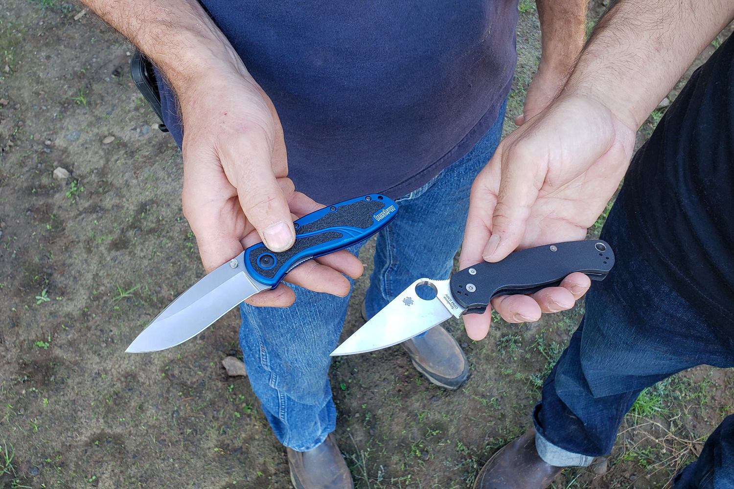 two backpackers each holding a pocket knife open to show the size and shape differences.