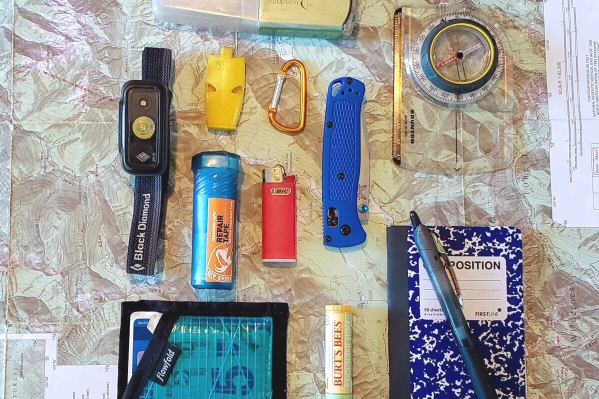 A backpacker's essential tools for a backpacking trip, including a small folding pocket knife